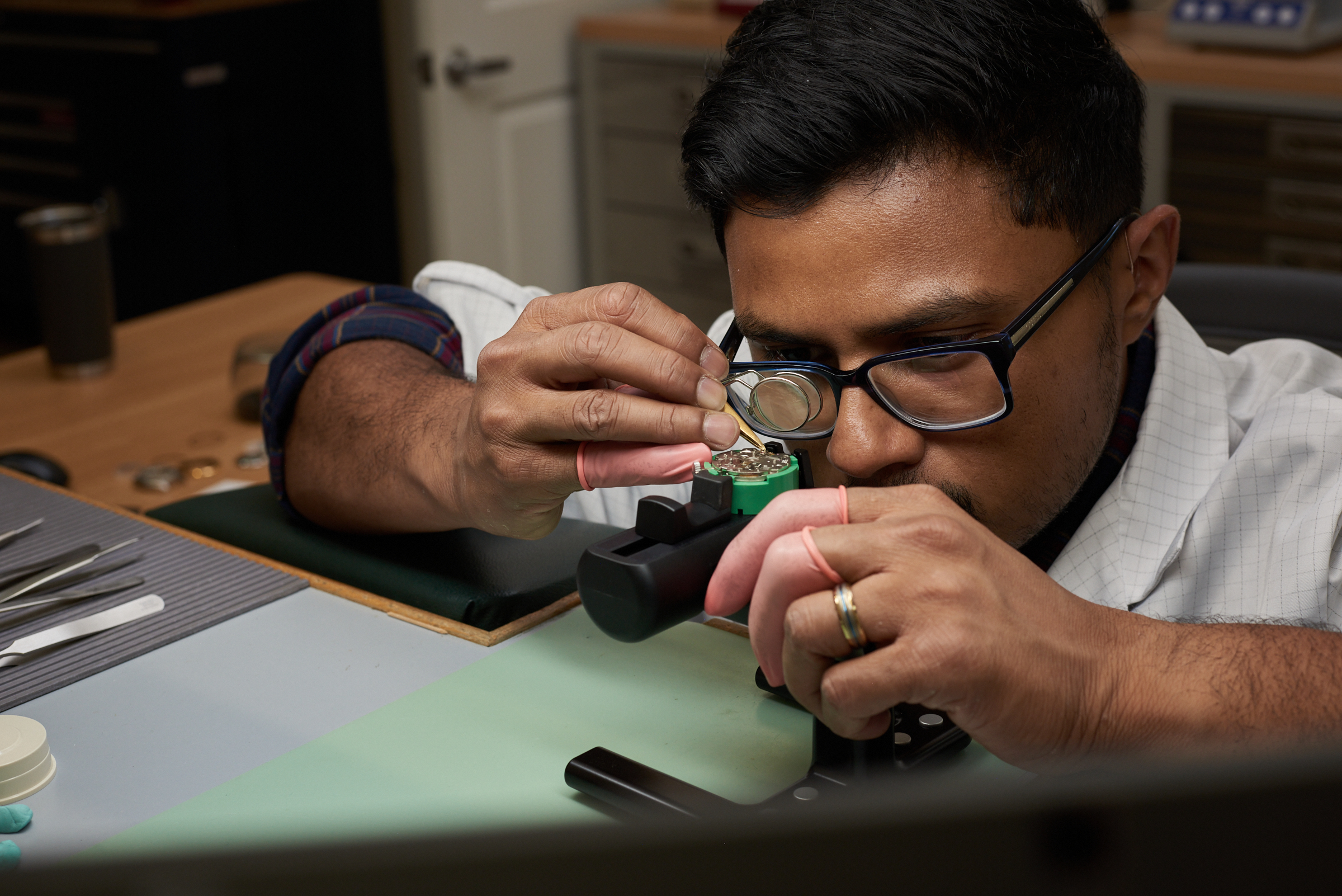 Watchmaker at a precision workbench from the legacy Atlanta service-center page