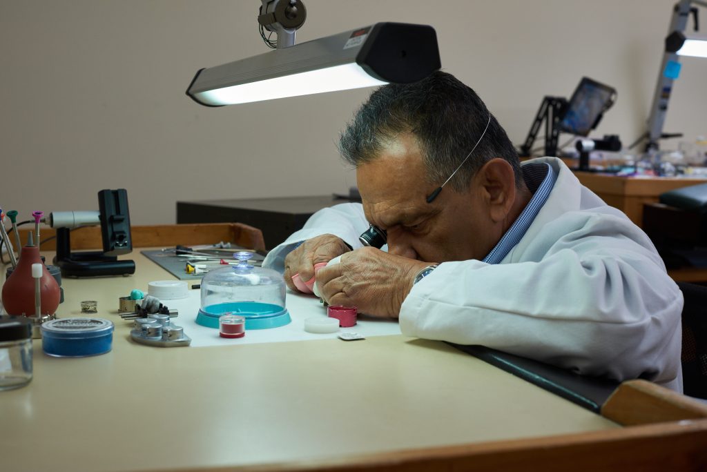 Watchmaker performing careful watch service at an illuminated workbench