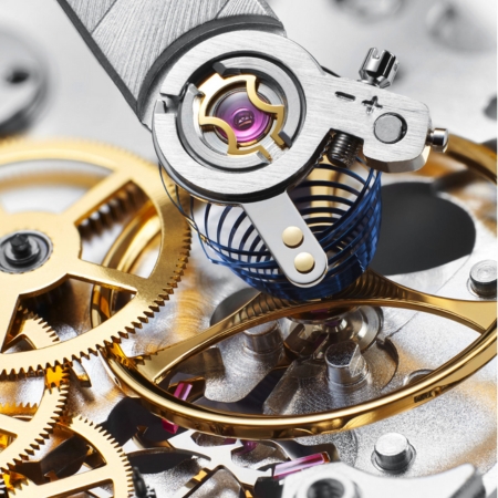 Close-up of a watch movement, balance assembly, gears, and precision service tools