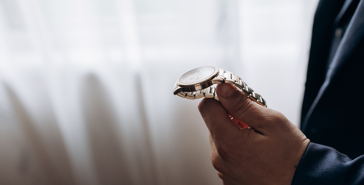 A man holding a gold watch in his band hesitant about shipping it for repair