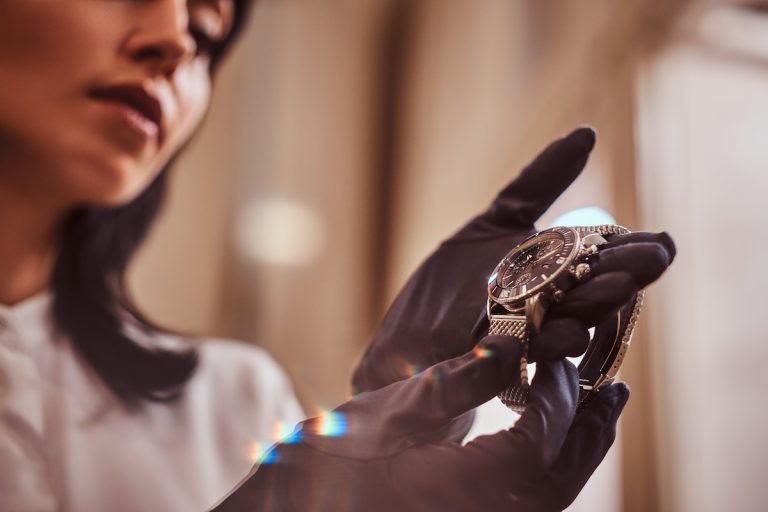 Seller holding a luxury watch in gloved hands